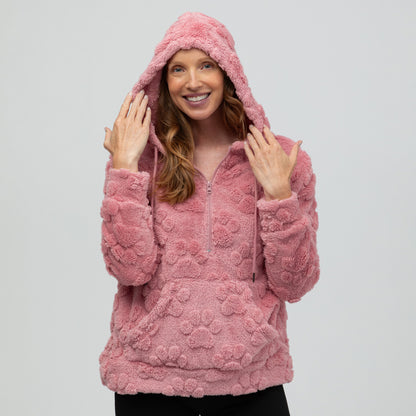 Woman wearing a pink paw print textured hoodie with a kangaroo pocket, and a white background.
