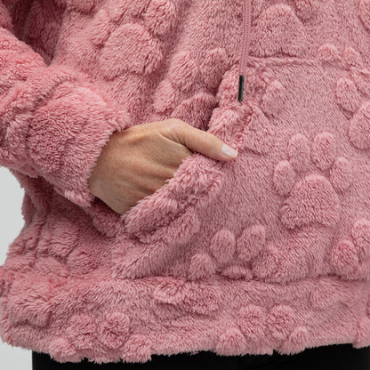 Close-up of a pink textured fleece hoodie with a hand reaching into the kangaroo pocket.