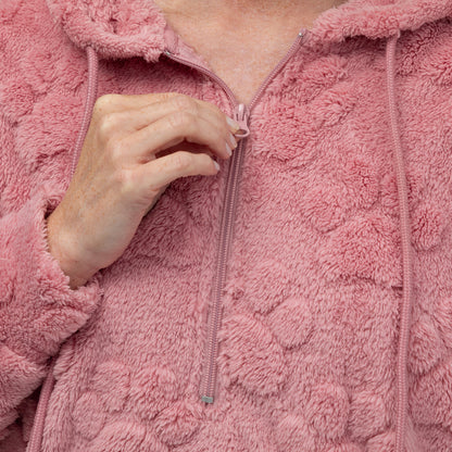 Close-up of a person wearing a pink fuzzy jacket with a hand zipping it up.