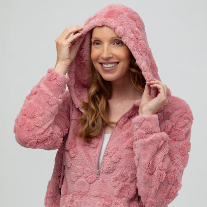 Woman wearing a pink fluffy paw print fleece hoodie against a white background