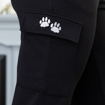 Black cargo pants with white paw prints embroidered on a pocket