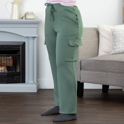 Person wearing green cargo pants with two embroidered paw prints on the pocket, standing in a living room setting.