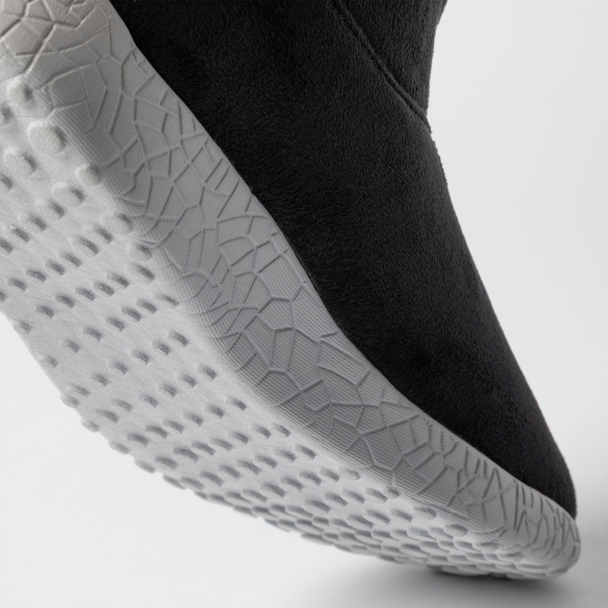 Close-up of a black slip on boot with gray sole on a light gray background