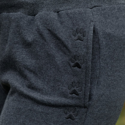 Dark gray pants with paw print design on a blurred green background