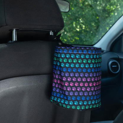 Car garbage holder cover with rainbow paw pattern in a car interior hanging on the headrest of the front seat. 
