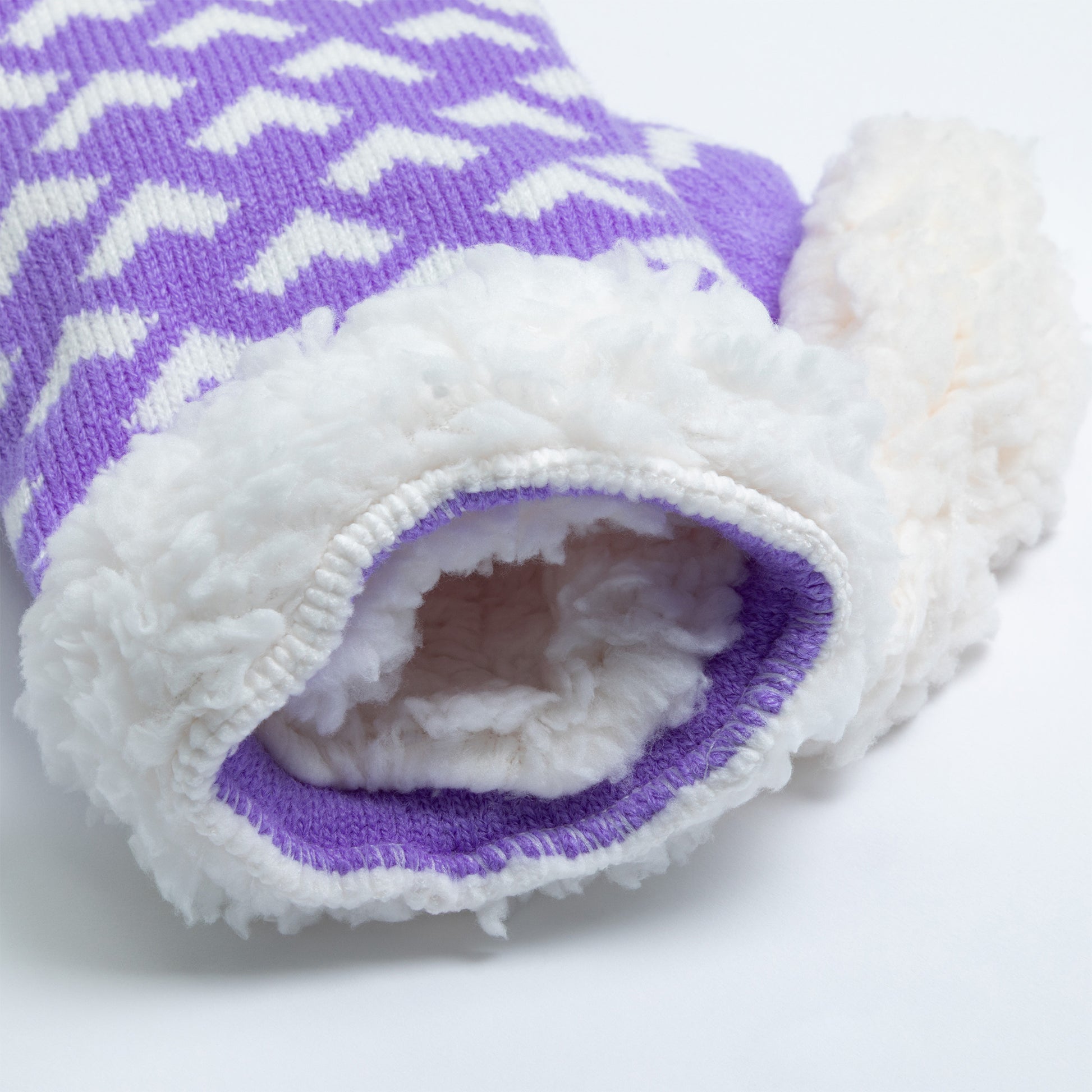 Purple and white pair of slipper socks with a fuzzy lining on a light background