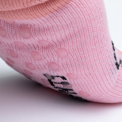 Close-up of pink socks with traction dots underneath on a light gray background