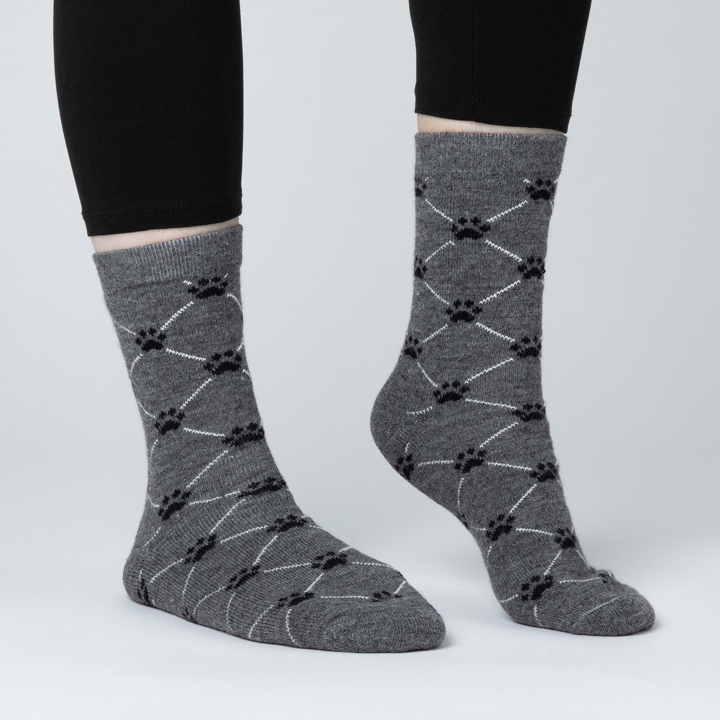 Gray socks with black paw print pattern worn by a person on a light gray background