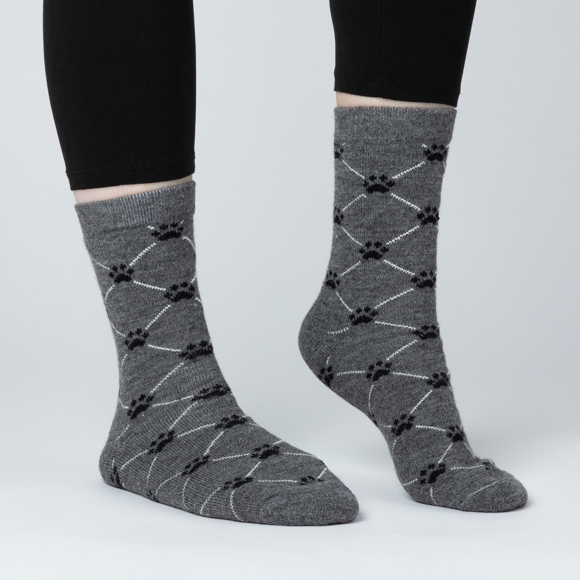 Gray socks with black paw print pattern worn by a person on a light gray background