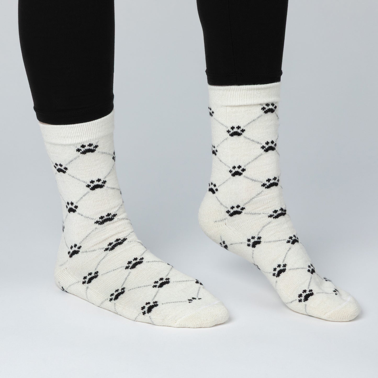 White socks with black paw print pattern worn by a person on a light gray background