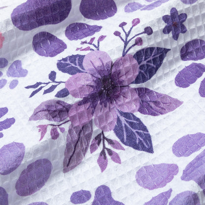 Close-up of a dish towel with purple floral design on a textured white background