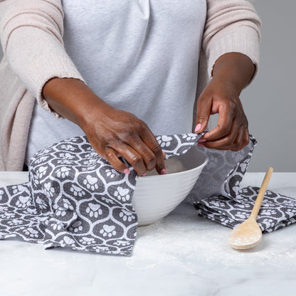 Person preparing food with a bowl and spoon on a paw print patterned towel