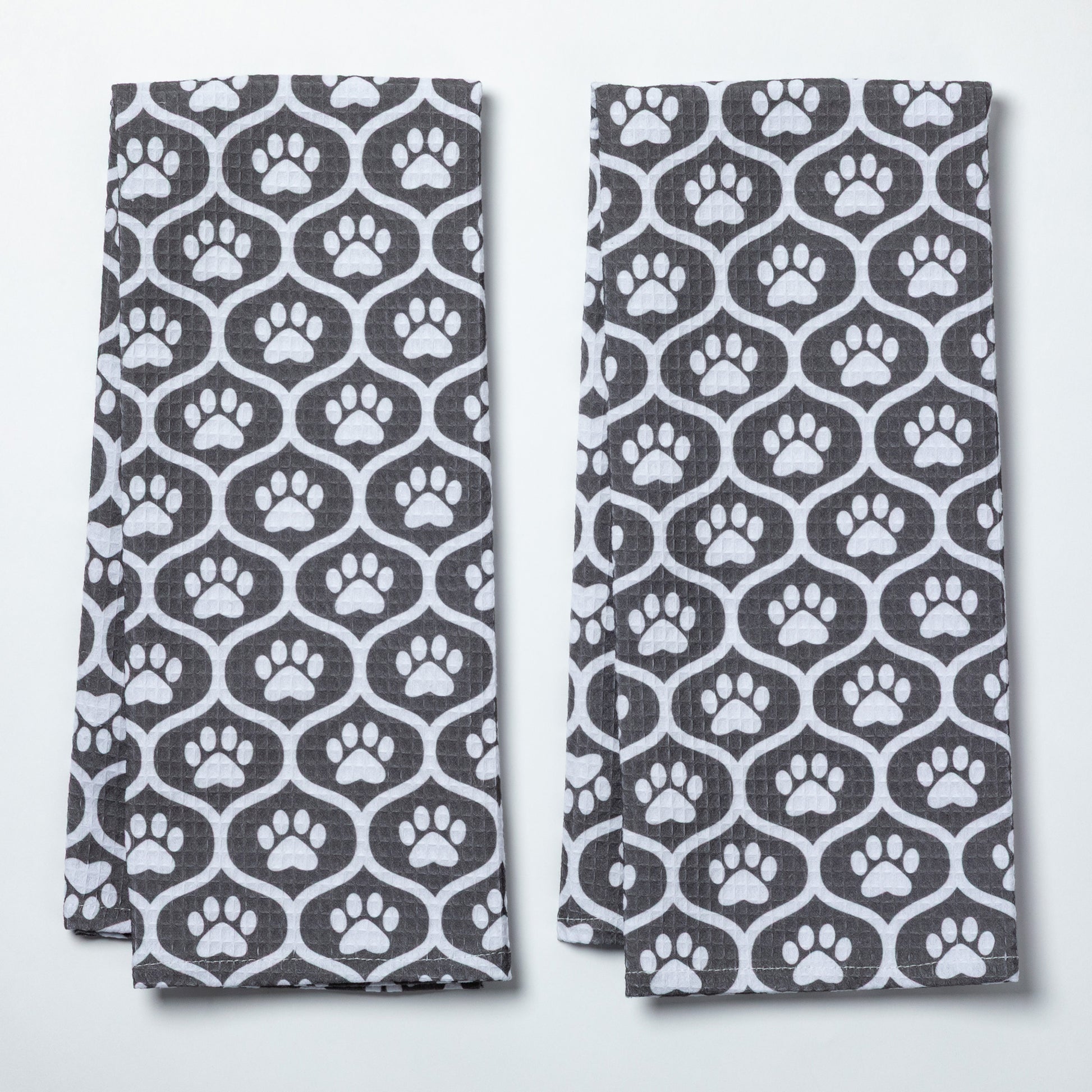 Two folded towels with a pattern of white paw prints on a gray background