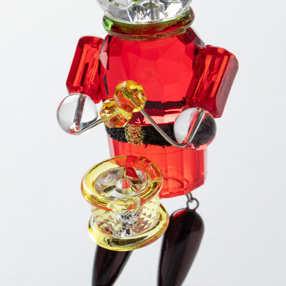Colorful nutcracker playing a drum with red, gold, and black colors on a white background