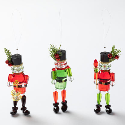 Three colorful glass nutcracker ornaments on a white background