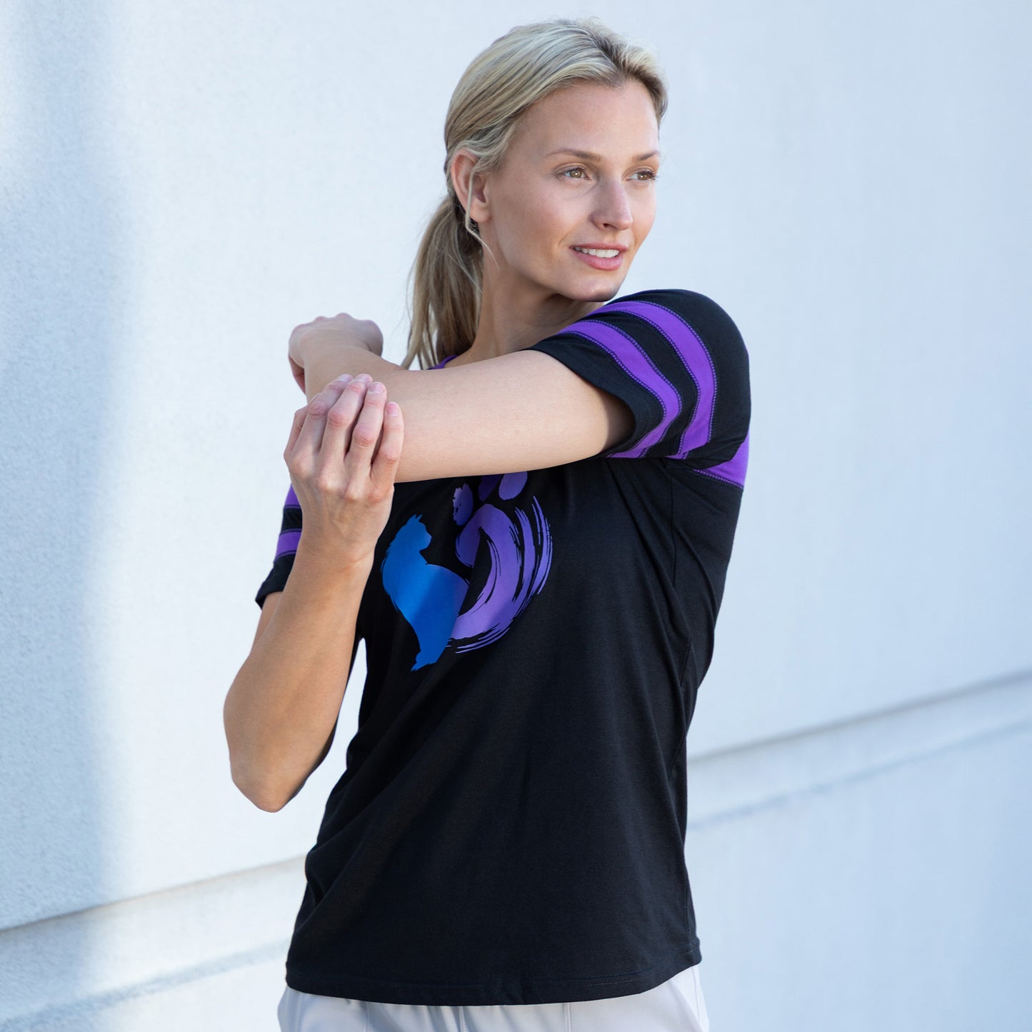Woman wearing a black shirt with a cat and paw design, against a light background outside.
