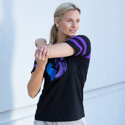 Woman wearing a black shirt with a cat and paw design, against a light background outside.