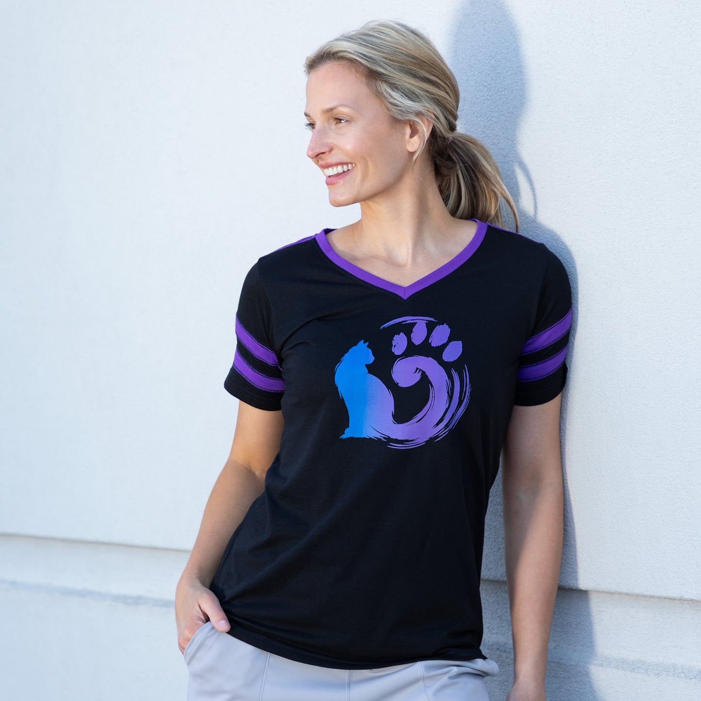 Woman wearing a black shirt with a cat and paw design, against a light background outside.