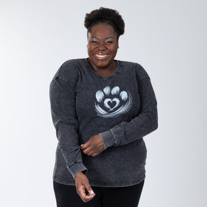 Person wearing a dark gray long sleeve tee with a heart design on a white background