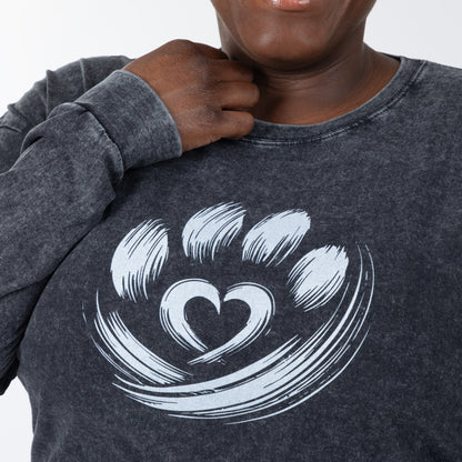 Person wearing a dark gray sweatshirt with a white paw print design on a plain background