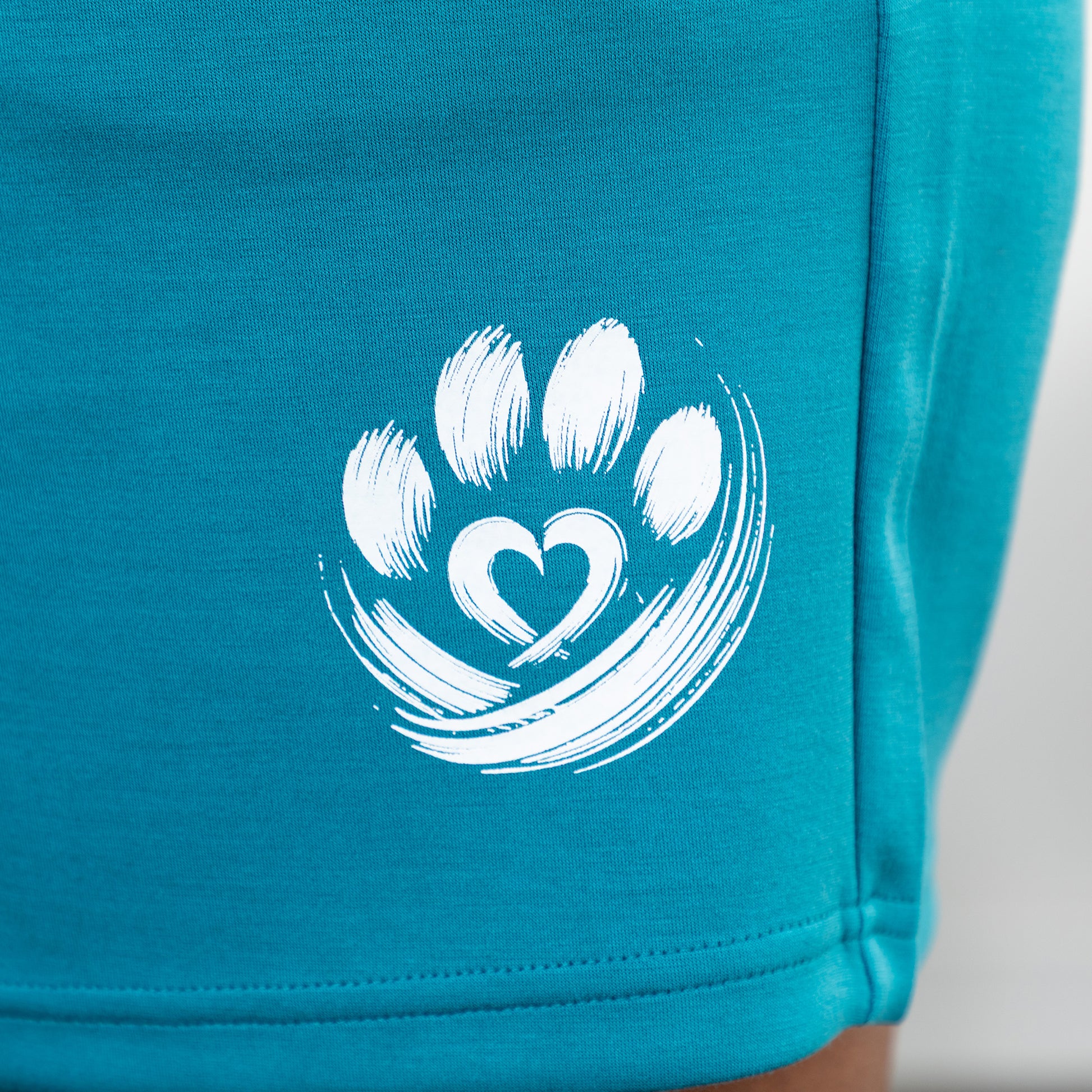 Teal shorts with a white paw print design on a plain background.