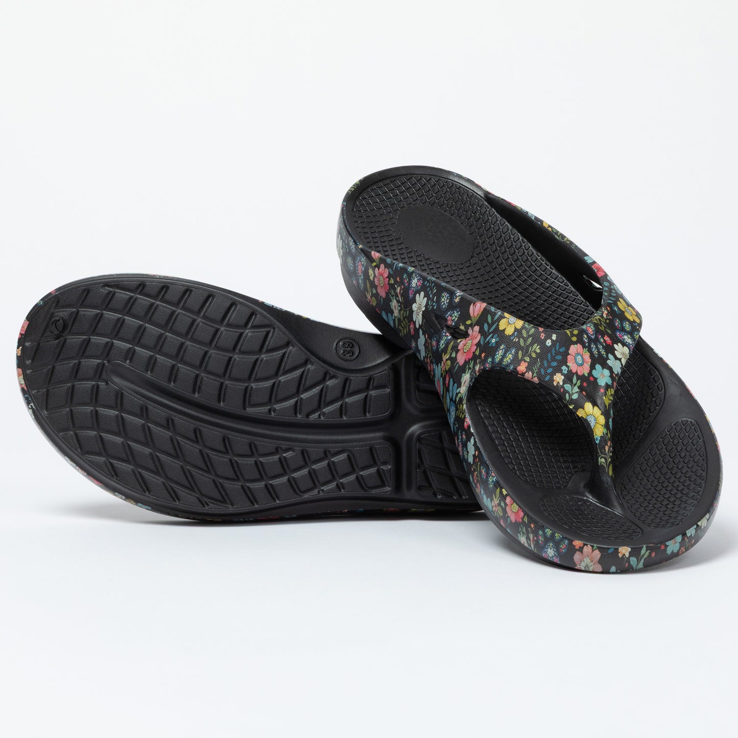 Pair of floral-patterned sandals with black soles on a white background