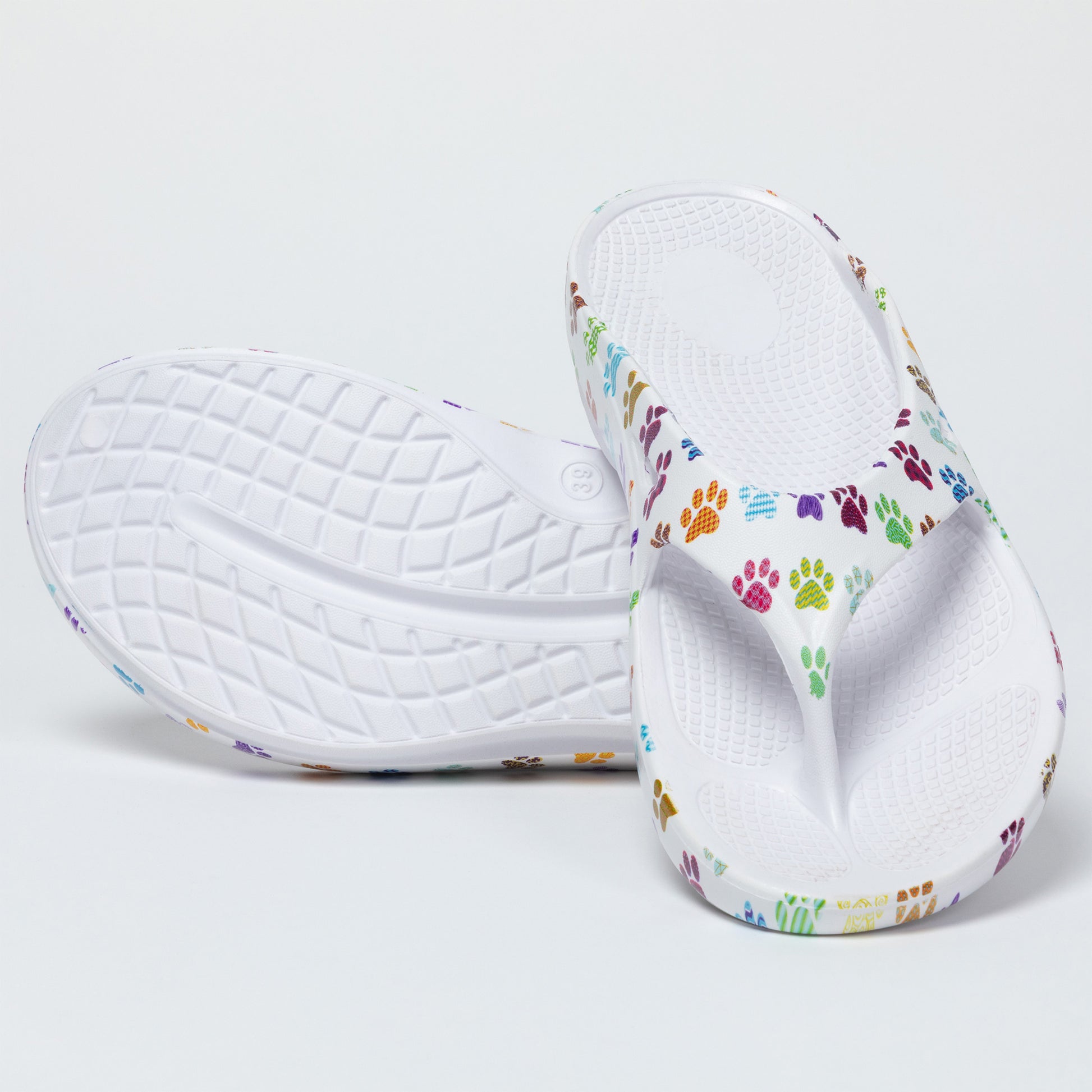 Pair of white flip flops with colorful paw prints on a light gray background