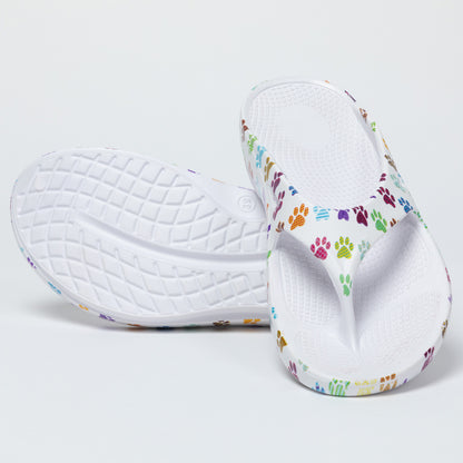 Pair of white flip flops with colorful paw prints on a light gray background