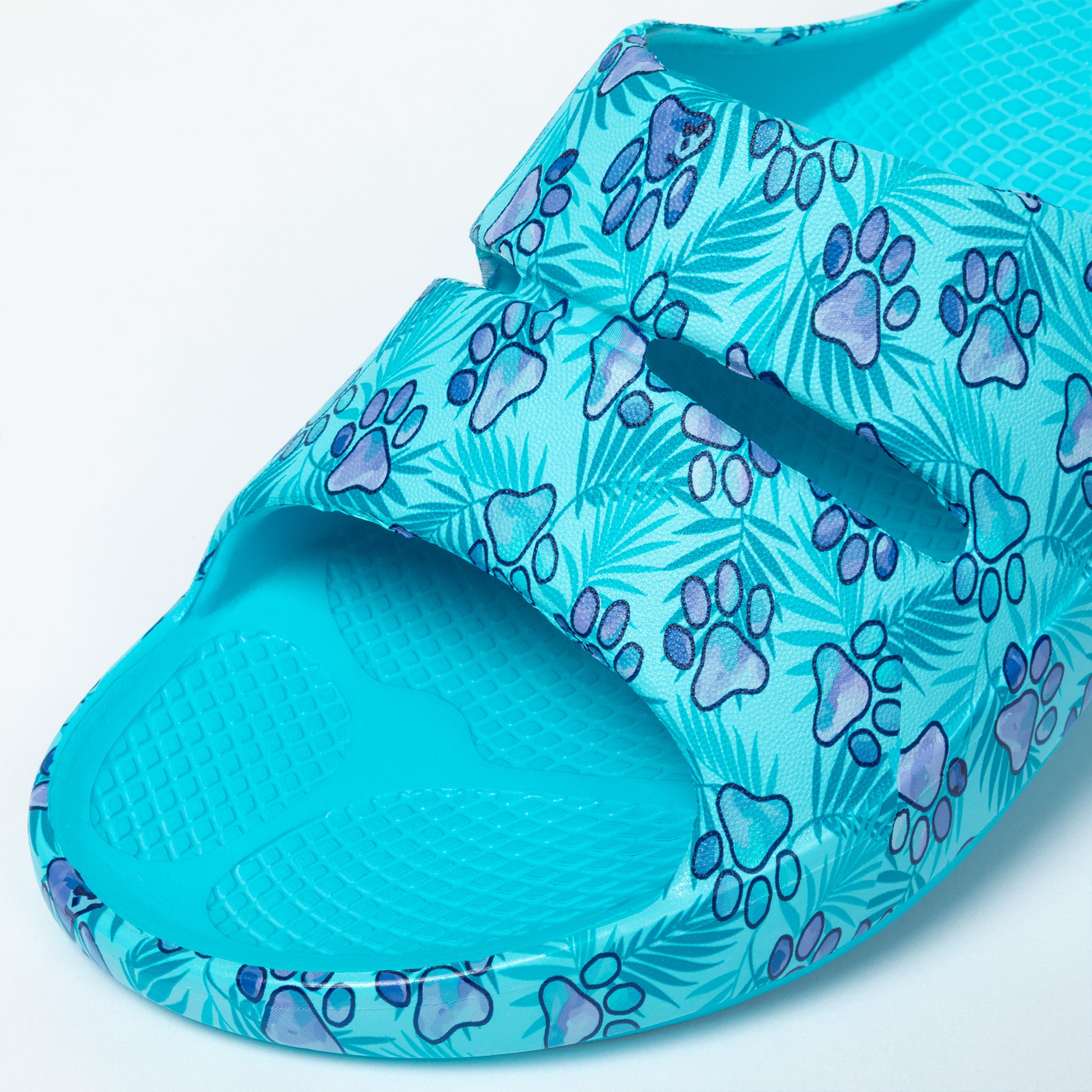 Blue slide sandal with paw print pattern on a light blue background