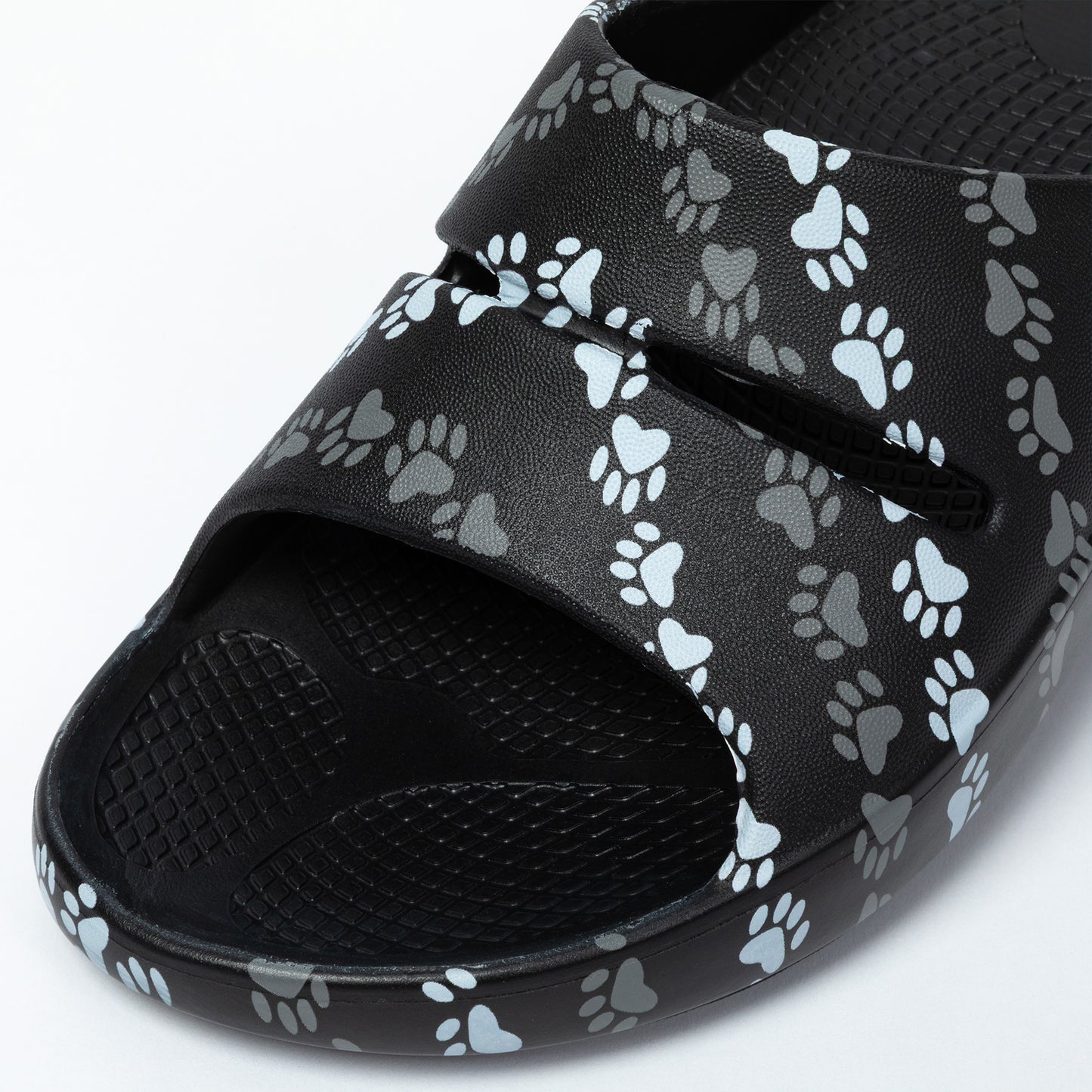 Black slide sandal with paw print pattern on a white background