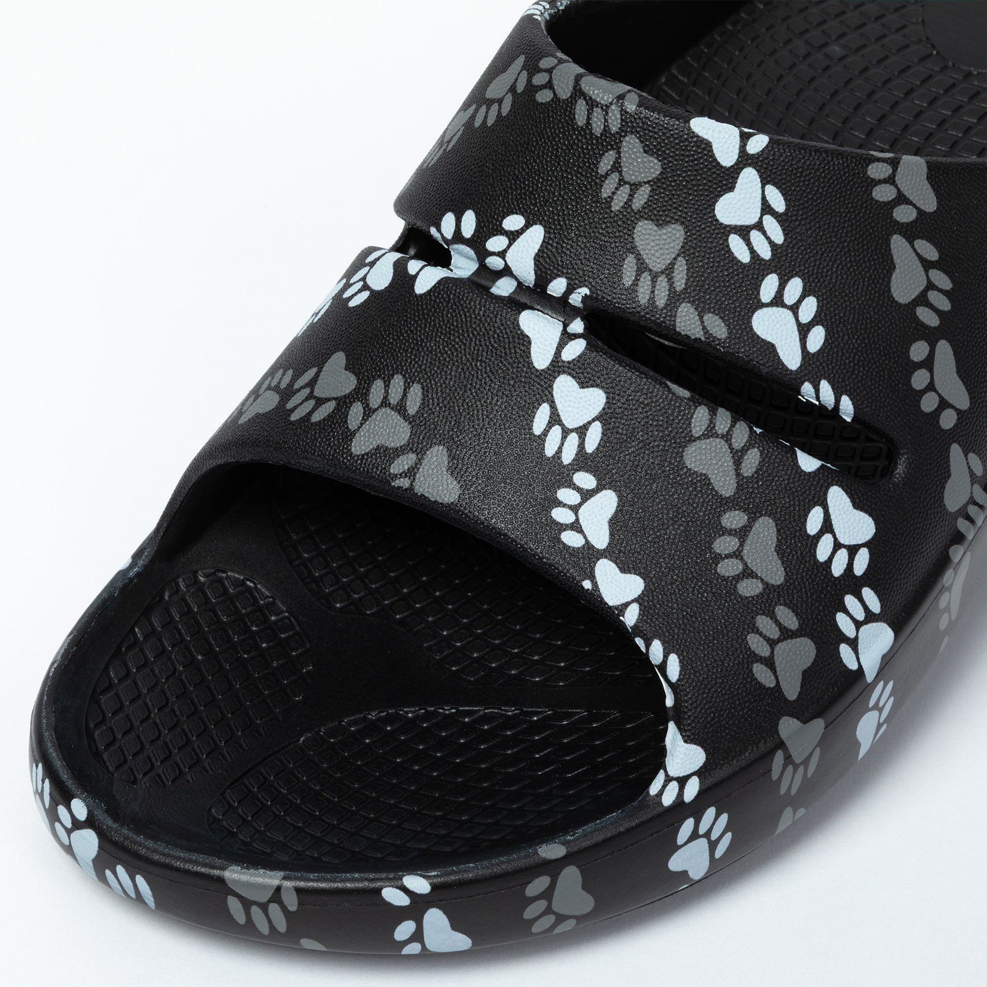 Black slide sandal with paw print pattern on a white background