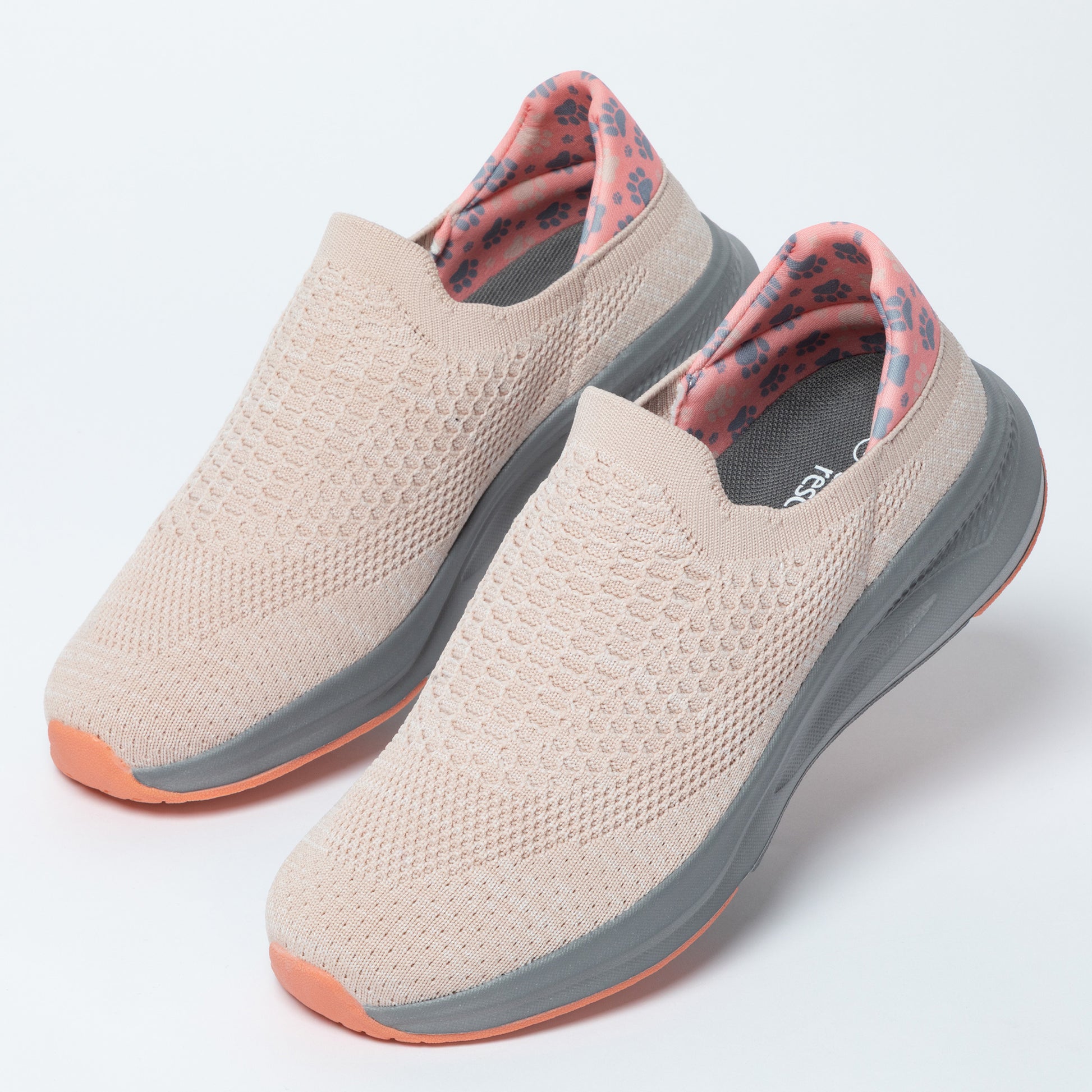 Pair of beige slip-on shoes with gray soles on a white background