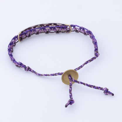Purple braided bracelet with a gold charm on a white background