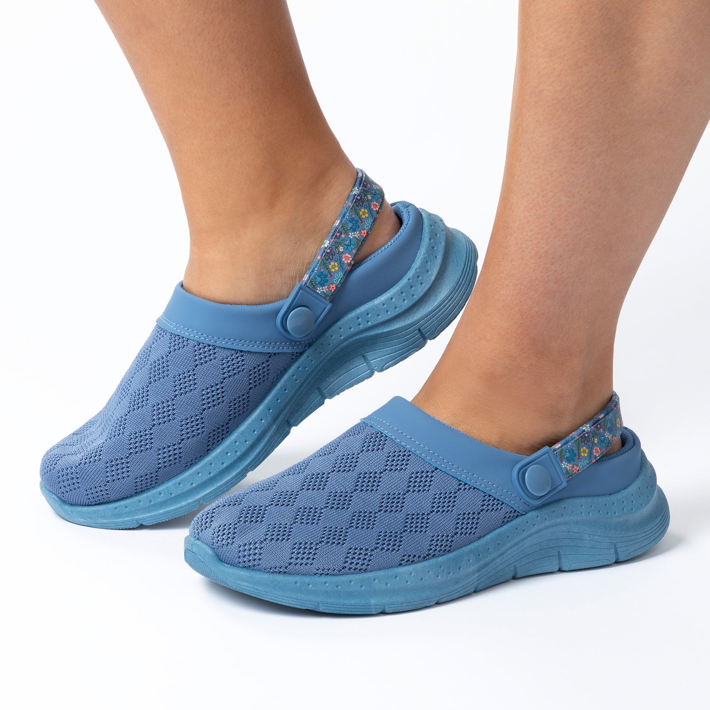 Blue clogs worn on feet with a white background