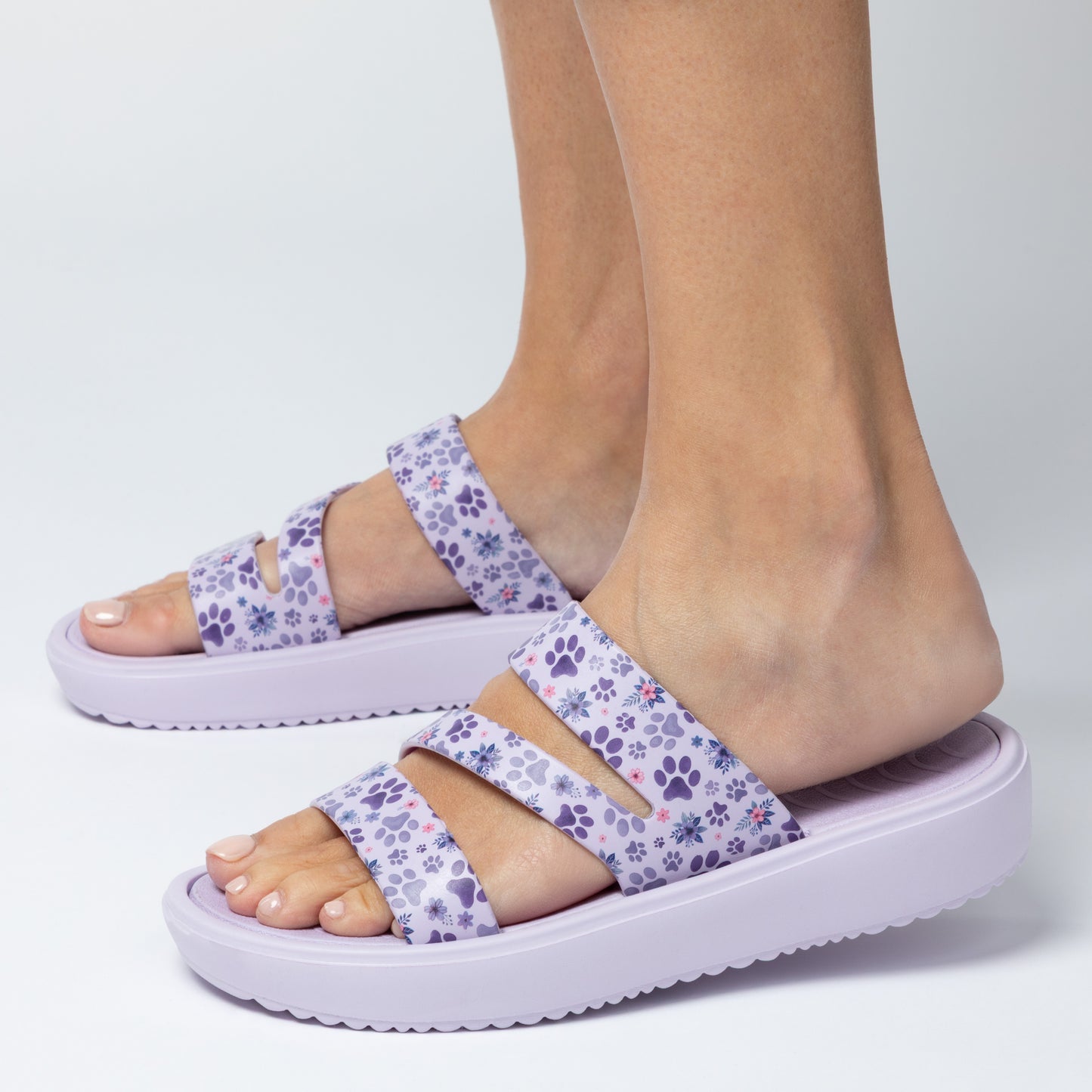 Purple sandals with floral pattern worn by a person on a white background