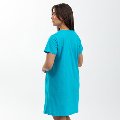 A woman in a bright turquoise nightgown stands facing away, showcasing a relaxed fit.
