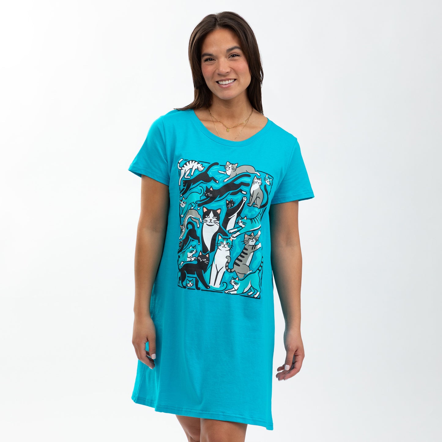 Smiling woman in a teal cat-themed nightgown stands against a white background.