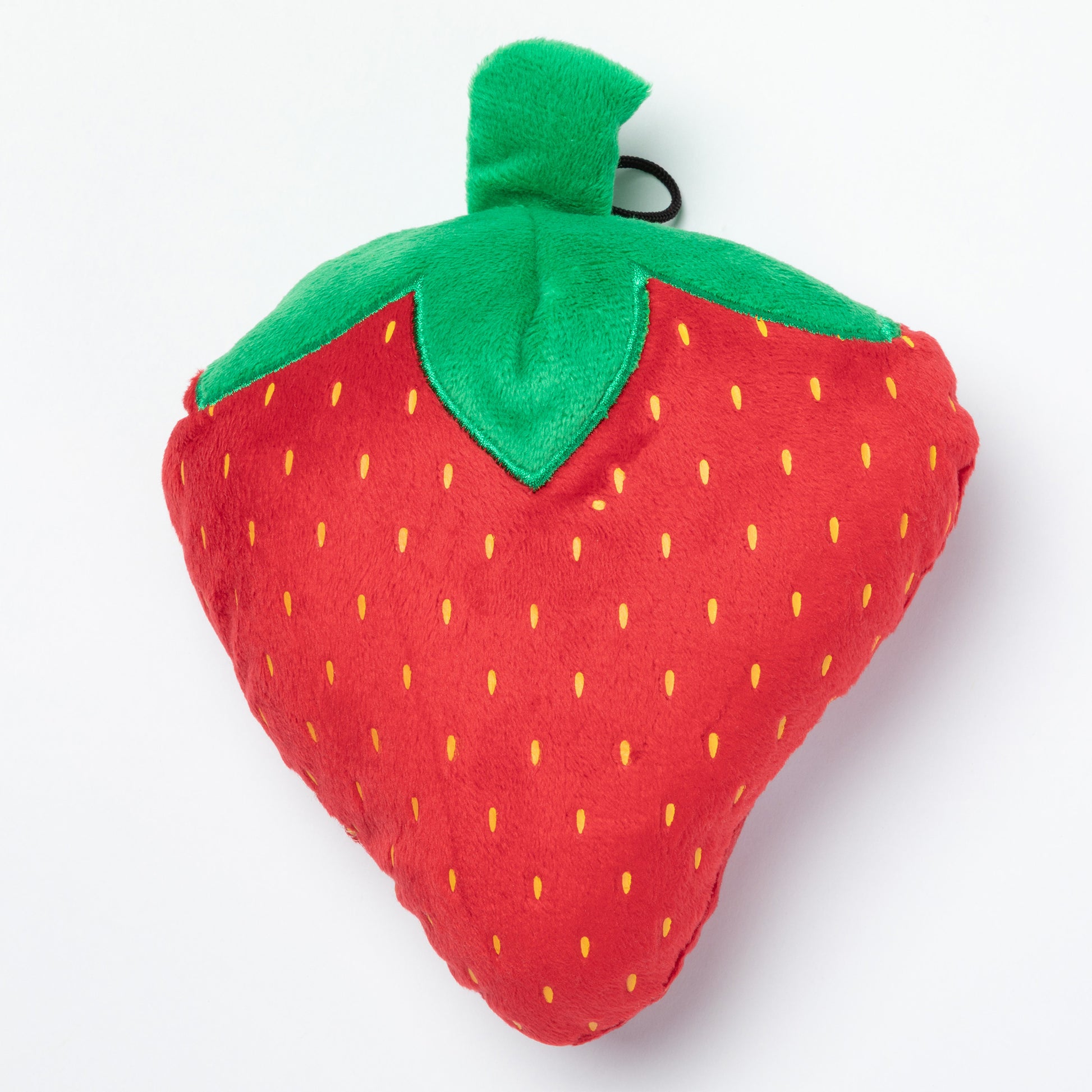 Plush strawberry dog toy with green stem on a white background