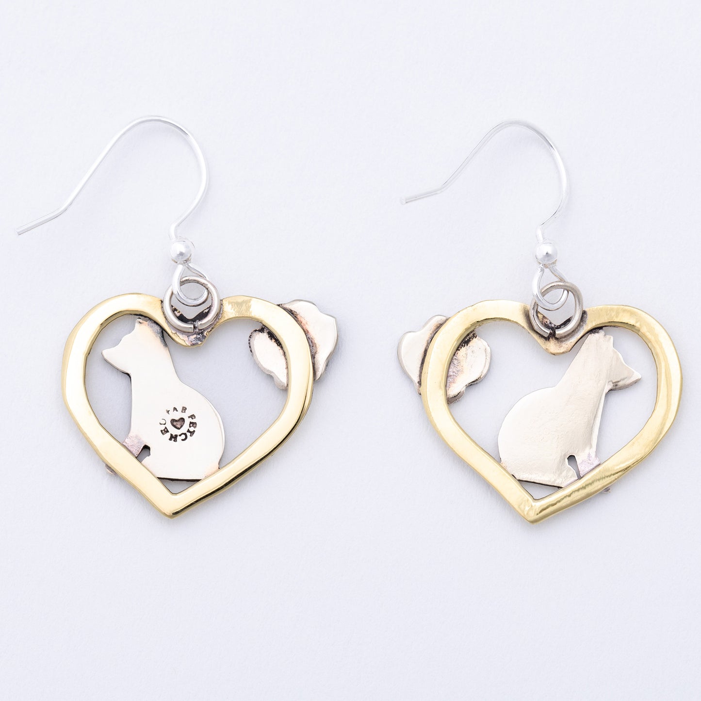 The back of heart-shaped earrings with dog designs on a white background
