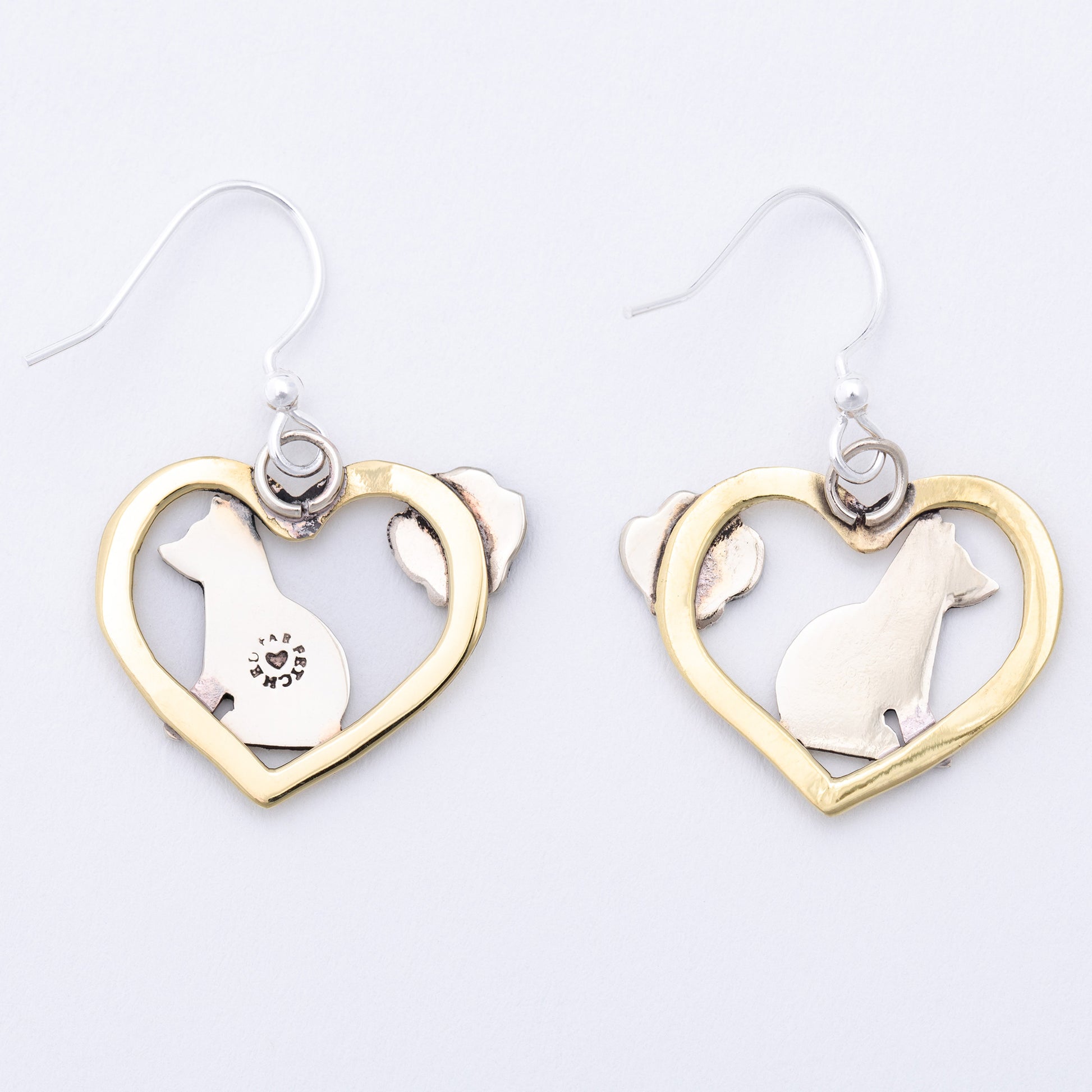 The back of heart-shaped earrings with dog designs on a white background