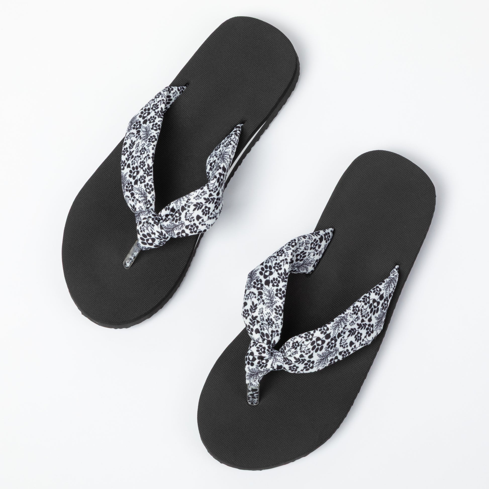 Black flip-flops with floral and paw print design on a white background
