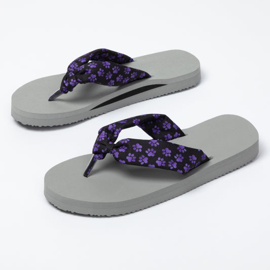 Pair of gray flip-flops with purple paw print straps on a white background