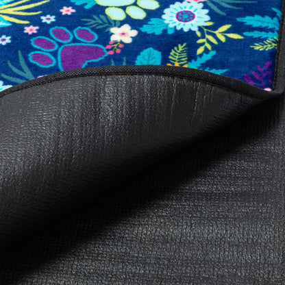 Close-up of a black textured waterproof backing of a pet blanket with a colorful floral paw pattern on the front.