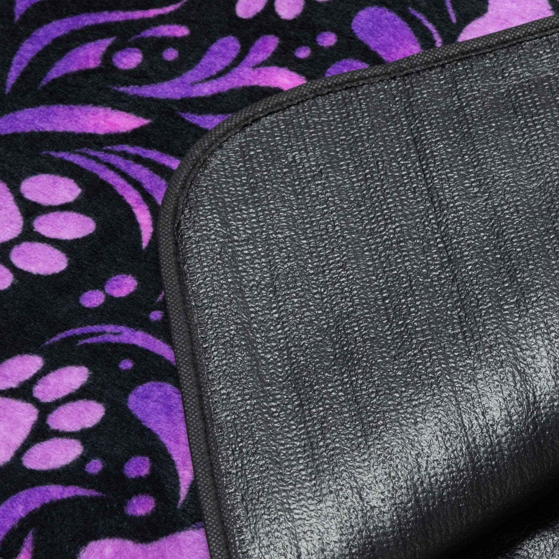 Black textured waterproof backing on a purple and black patterned fleece blanket.