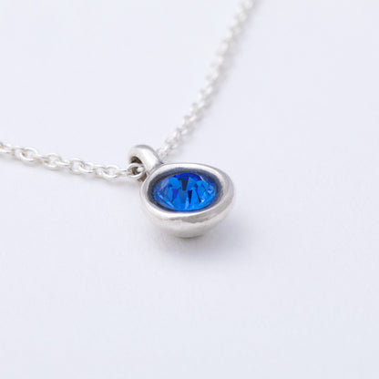 Silver necklace with a blue gemstone on a white background