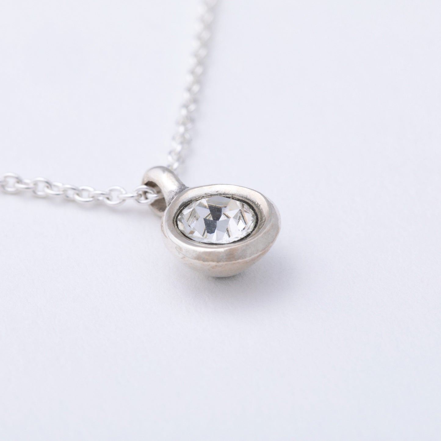Silver necklace with a round pendant on a light gray background