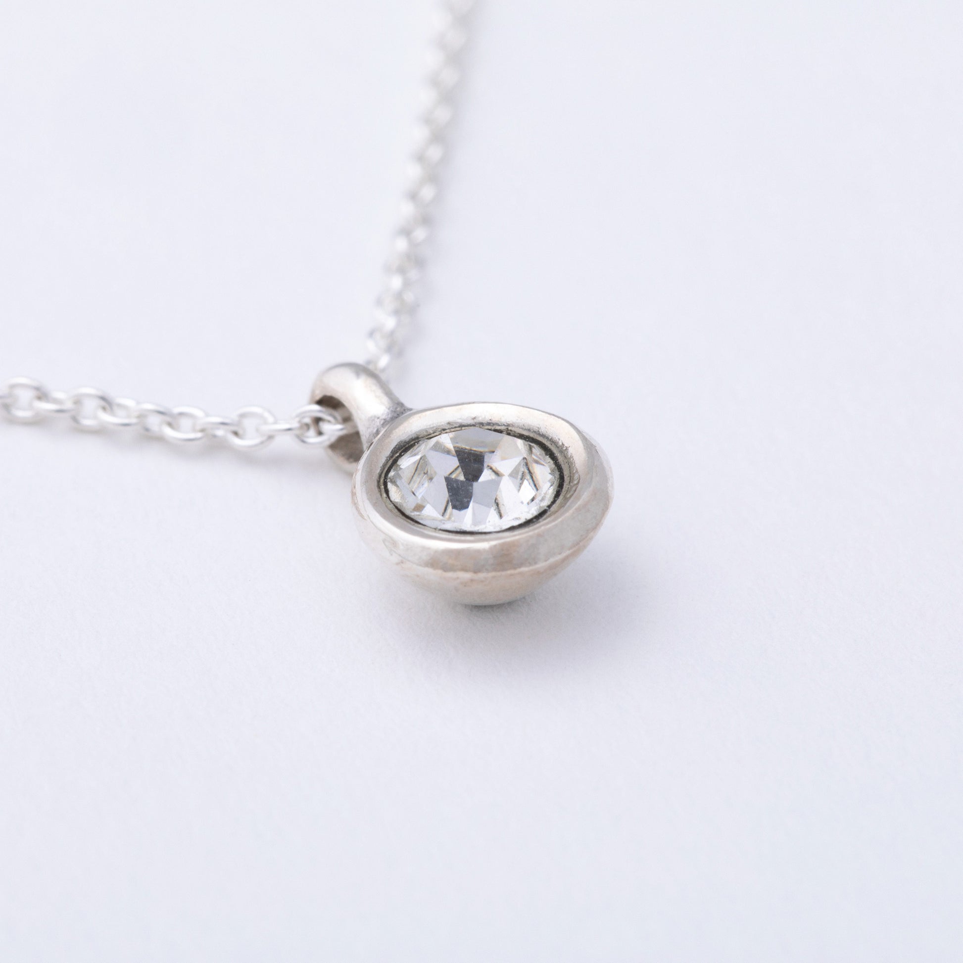 Silver necklace with a round pendant on a light gray background