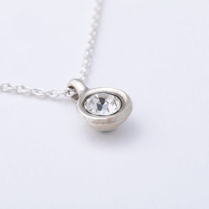 Silver necklace with a round pendant on a light gray background