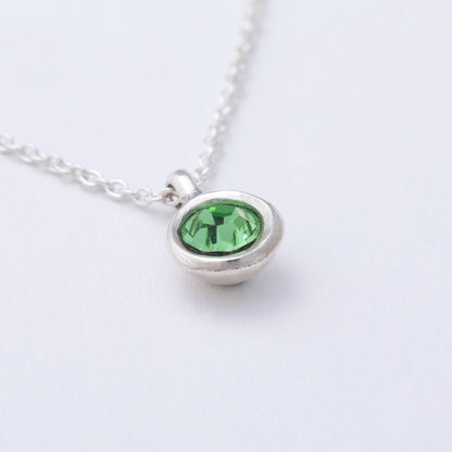 Silver necklace with a green gemstone pendant on a white background
