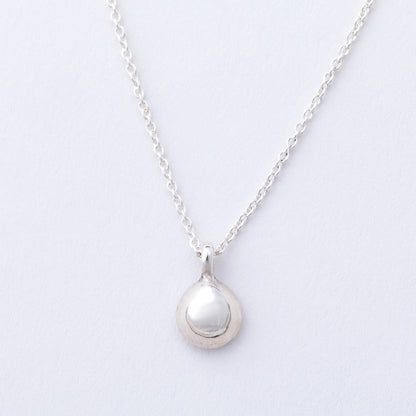 Silver necklace with a round pendant on a light gray background